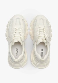 Witte sportieve schoenen met een gestructureerde bovenkant, voorzien van mesh panelen, dikke rubberen zolen en een geïntegreerd vetersysteem. Patroonelementen zijn zichtbaar.