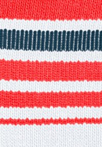 Gros plan sur un tissu tricoté avec des rayures horizontales en rouge, blanc et bleu marine, montrant des motifs de points texturés.