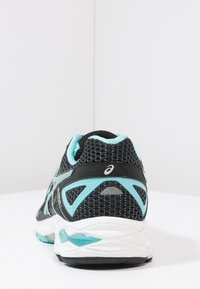 Scarpe da corsa in mesh nero con accenti turchesi. Presentano una suola bianca imbottita e dettagli riflettenti. Progettate per comfort e supporto.