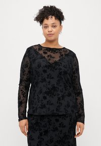 T-shirt noir à manches longues avec un superposition florale transparente, dotée d'un col rond, d'un tissu texturé et d'une coupe ample.