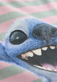 Cotton fabric featuring a close-up print of a blue cartoon character's face with large black eyes and exposed white teeth, against a striped background.