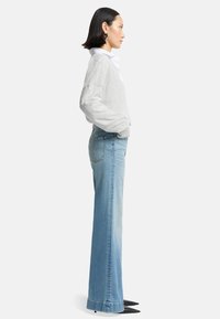 Light gray sweater with a relaxed fit, white collar, paired with light blue straight-leg jeans and black pointed-toe heels.