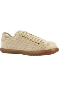 Sneakers perforati beige con lacci beige e una suola in gomma marrone flessibile. Texture liscia con design aerodinamico e punta arrotondata.