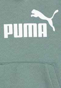 Zelena dukserica s kenguruu džepom, rebrastim manžetama i donjim rubom, s bijelim "PUMA" logotipom i siluetom skakačkog pumam.