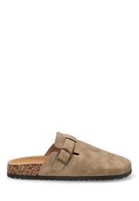 Zapato de ante beige tipo slip-on con suela de corcho, detalle de hebilla ajustable y diseño con recortes. Textura suave con puntera redondeada.