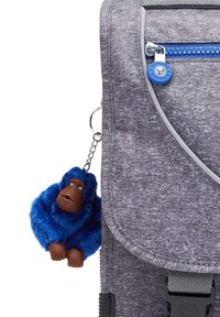 Grå tygryggsäck med en blå dragkedja, med en fluffig blå apan nyckelring fäst. Ryggsäcken har en elegant, strukturerad design.