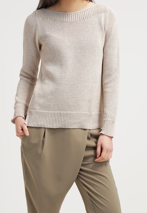 Hellbeige gestrickter Pullover mit weitem Ausschnitt, gerippten Bündchen und Saum, getragen über lockeren olivgrünen Hosen. Glatte Textur, lässige Passform.