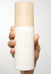 ILIA The Cleanse, en cylindrisk hvid flaske med en beige hætte, har minimalistisk tekst og en glat mat finish.