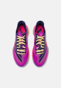 Scarpe da sport con una vivace tomaia rosa e dettagli in blu navy, tessuto testurizzato, lacci gialli e suola traslucida.