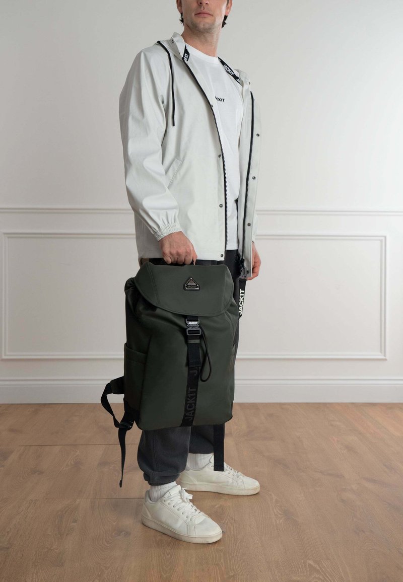 Zaino verde realizzato in materiale resistente, con apertura a pieghe, spallacci regolabili, tasche laterali e dettaglio con logo sulla tracolla.