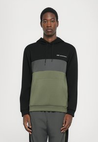 Hoodie su kapišonu, turintis juodą viršutinę dalį, pilką vidurinę dalį ir alyvuogių žalią apačią. Pagamintas iš minkštos medžiagos su priekiu kišene ir logotipo detale.