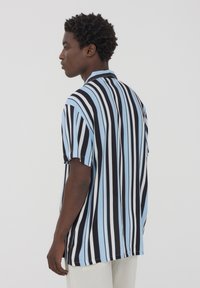 Camicia a maniche corte con righe verticali blu, nere e bianche, dal taglio rilassato e colletto. Tessuto morbido e leggero.
