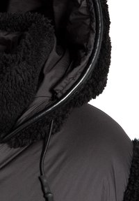 Czarna kurtka z kapturem o puszystej, teksturowanej powierzchni, gładkiej podszewce, regulowanym sznurkiem oraz kontrastowymi wykończeniami.