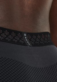 Shorts de sport ajustés noirs avec une taille texturée, arborant une étiquette "RUSH" et un motif en maille le long du haut.