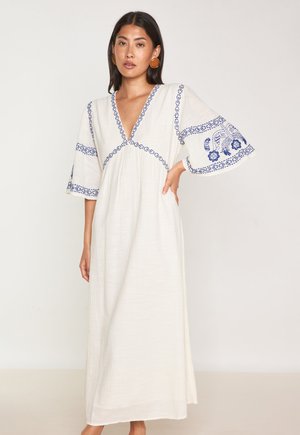 Ein langes, cremefarbenes Kleid mit V-Ausschnitt, bestickten blauen Blumenmustern und weiten Glockenärmeln, hergestellt aus einem leichten Stoff.