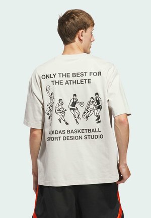 Hvid bomulds t-shirt med et grafisk tryk af basketballspillere på ryggen, med sort tekst over og under illustrationen.