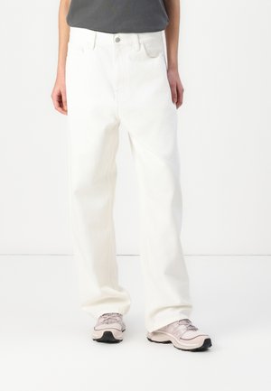 White denim pants with a loose fit, featuring front pockets, a zipper fly, and subtle stitching details. Paired with light pink sneakers.