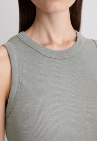 Jasnozielony, ribbed top bez rękawów z okrągłym dekoltem, prezentujący gładką teksturę i dopasowany krój.