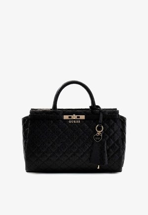 Czarna pikowana torebka na dwa uchwyty, z pozłacaną tabliczką z logo „GUESS” oraz brelokiem w kształcie serca wiszącym na jednym z uchwytów.
