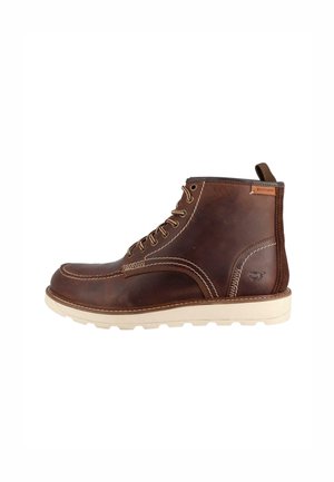 Braune Lederstiefeletten mit genähten Details, weißer Gummisohle, Schnürdesign und einer Zuglasche an der Rückseite.