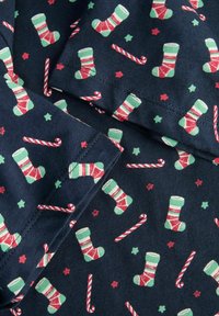 Tela azul marino con un motivo repetitivo de medias navideñas verdes y rojas, bastones de caramelo y pequeñas estrellas de varios colores.