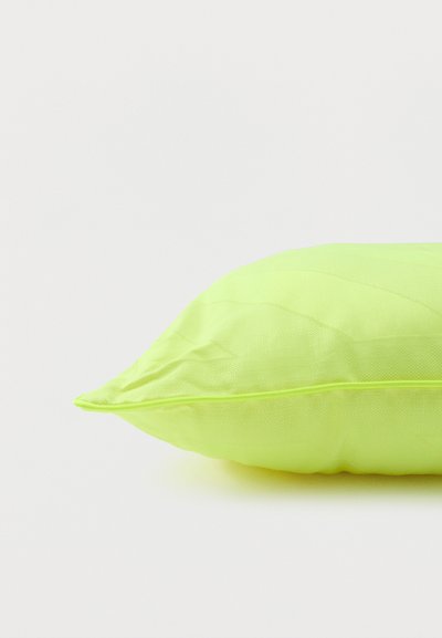 Φωτεινό πράσινο μαξιλάρι σε ορθογώνιο σχήμα με εμφανείς ραφές και περιγράμματα, το οποίο βρίσκεται πάνω σε λευκή επιφάνεια.