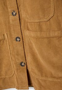 Veste en velours côtelé marron clair vue de face, montrant des boutons et deux poches plaquées avec une texture verticale à nervures visibles.