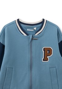 Blauer Reißverschlussjacke mit einem marineblauen Ärmel, einem gerippten Kragen und einer braunen "P"-Applikation auf der Vorderseite. Weicher Stoff mit glatter Textur.