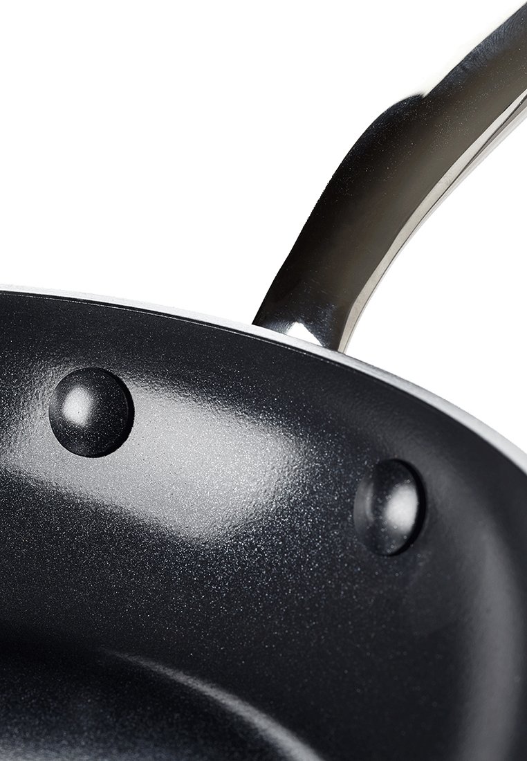 Zwarte anti-aanbak koekenpan met een gladde binnenkant, zilveren handvat en twee ronde klinknagels voor een stevige bevestiging.