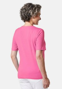 Korte mouwen roze T-shirt van zacht katoen, met een ronde halslijn en een getailleerde snit, gedragen met witte broeken.