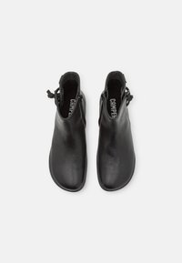 Paire de bottines en cuir noir avec fermetures éclair sur les côtés et bouts arrondis, vue de dessus sur fond blanc.