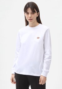 Hvid langærmet t-shirt lavet af bomuld. Har et lille farverigt logo på brystet, rund halsudskæring og en afslappet pasform.