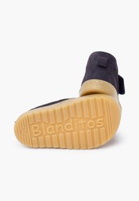 Černá semišová bota s texturovanou gumovou podrážkou. Má ploché tkaničky a poutko pro snadné obouvání. Na podrážce je vyraženo "Blanditos".