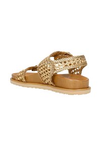Sandali intrecciati in tono dorato con fasce incrociate, suola piatta color nocciola e superficie strutturata. Presentano un design minimalista.