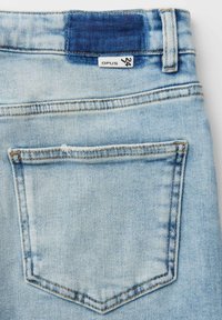 Lichtblauwe spijkerbroek achterzak met een maat 24 label en een donkerblauwe gestikte patch boven de tailleband.