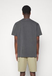 Grijze katoenen T-shirt met een relaxte pasvorm, korte mouwen en een ronde halslijn, gecombineerd met beige cargoshorts met zakken.