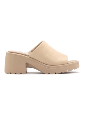Beige mule sandal met dikke hak, gesloten neus, dikke zool en gestructureerd bovenwerk, getoond op witte achtergrond.