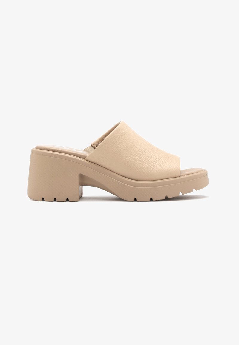 Mule beige à talon épais, bout fermé, semelle épaisse et dessus texturé, présentée sur fond blanc.