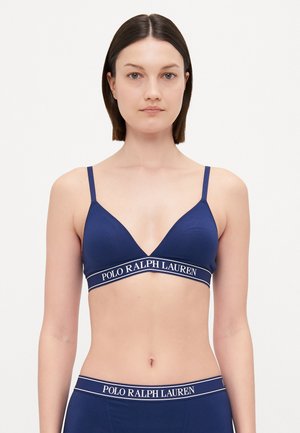 Tums zilas trīsstūra bralete ar plānām siksnām, kurai ir teksturēta auduma virsma un kontrastējoša balta logotipa josla zem krūtīm.