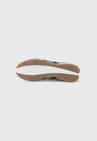 Shoe sole featuring a textured rubber design with a brown outsole and white midsole, alongside a multicolored synthetic upper section.