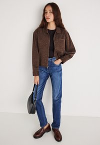 Ruda leopardo rašto striukė, juoda palaidinė, mėlyni džinsai, rudi lengvi batai, nešiojama juoda rankinė. Paprasta apranga su mišriomis tekstūromis ir spalvomis.