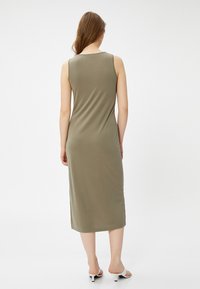 Olivgrünes, ärmelloses Maxikleid mit taillierter Silhouette, aus glattem Material gefertigt, mit Rundhalsausschnitt und einer Länge bis zur Mitte der Wade.