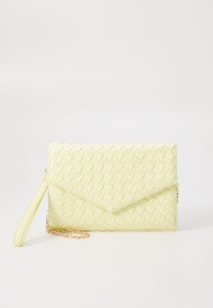 Bolso de mano trenzado de cuero amarillo claro con solapa tipo sobre, correa para la muñeca y detalle de cadena dorada sobre un fondo claro.