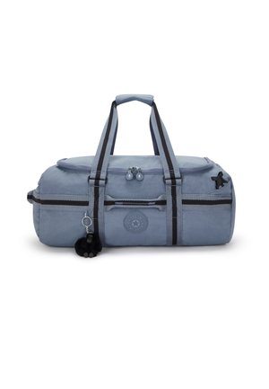 Blue duffel bag with gray accents, zipper closure, top handles, and detachable black pom-pom keychain; features a circular logo on front.