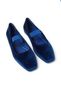 Ballerines en velours bleu avec un bout carré, dotées d'une large sangle élastique traversant le devant et d'une semelle intérieure lisse bleue.
