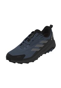 Zapatilla de running para exterior con un upper sintético de color azul oscuro con acentos negros, superficie texturizada y una suela negra resistente con patrones de tracción.