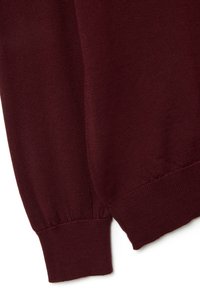 Maglione a costine color bordeaux con polsini e fondo a coste, texture liscia e un design aderente con una leggera elasticità.