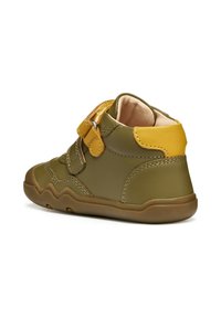 Scarpe da trekking per bambini in verde olivo con accenti gialli. Presentano una tomaia in pelle liscia, colletto imbottito e cinturini a strappo. Suola texturizzata.