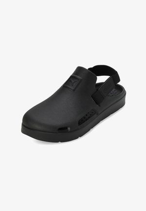 Scarpe slip-on nere realizzate in materiale simile alla gomma con una suola spessa, dotate di un cinturino sul retro e fori di ventilazione sui lati.