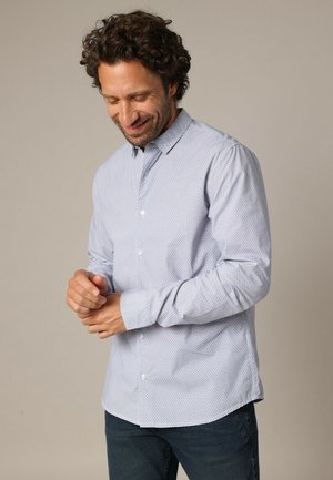 Chemise à manches longues bleu clair avec des boutons, dotée d'un petit motif répétitif, présentée avec un col évasé et un ourlet arrondi, fabriquée en tissu doux.